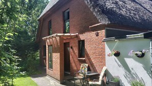 Una casa de ladrillo con un pequeño patio, una silla y plantas en macetas.