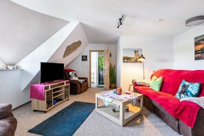 A living room with a TV, sofa, coffee table, and a staircase leading to another room.