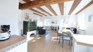 A spacious kitchen with wooden beams, a dining area with a table and chairs, and a living area with a sofa and a fireplace.