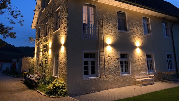A two-story building with a stone facade, multiple windows, and outdoor seating.