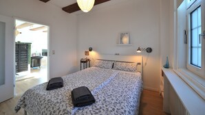 A bedroom with a bed, bedside lamps, a window, and a door leading to a balcony.