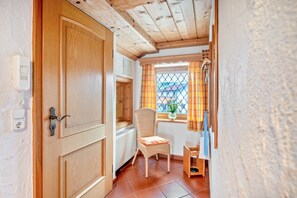 Une porte en bois, une chaise en osier et une fenêtre donnant sur un beau paysage.