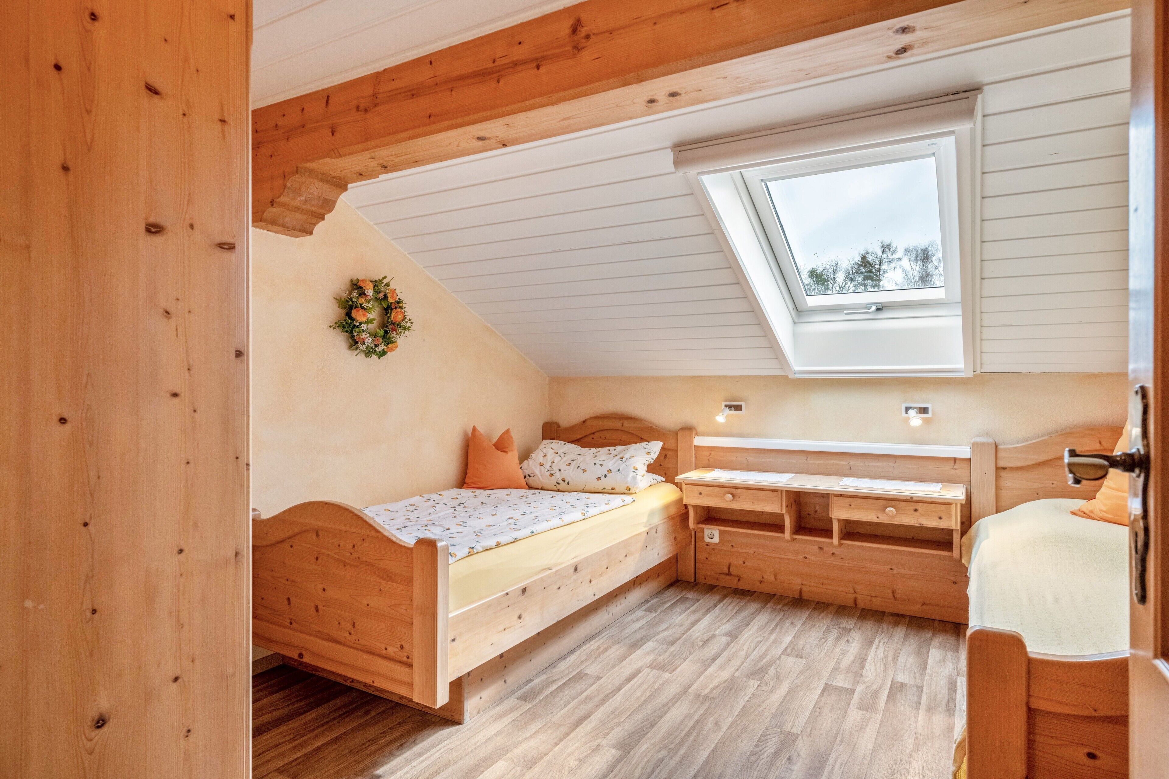 Een houten kamer met een bed, een bureau en een raam.