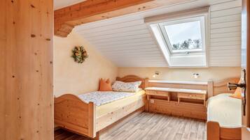 Een houten kamer met een bed, een bureau en een raam.