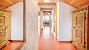 A corridor with wooden ceilings and tiled floors, leading to a door with floral designs.