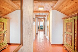 A corridor with wooden ceilings and tiled floors, leading to a door with floral designs.