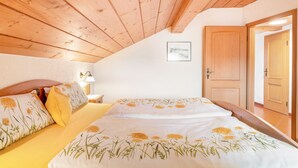 A bedroom with a wooden ceiling, a bed with floral bedding, a nightstand, and a door.