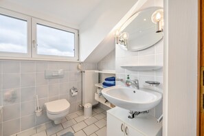 A modern bathroom with a toilet, sink, and window.