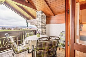 Une terrasse couverte avec une cheminée en pierre, des sièges d’extérieur et une vue sur le paysage.