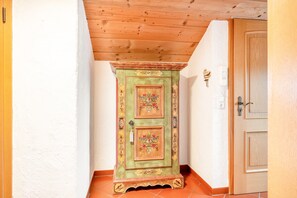 Una puerta de madera con un panel decorativo, una pequeña luz empotrada en la pared y un suelo de baldosas.