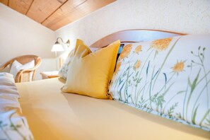 Una cama con ropa de cama floral, un cojín amarillo y un cabecero con estampado de flores.
