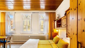 Una habitación con una cama, un armario de madera, un radiador y una ventana con cortinas.