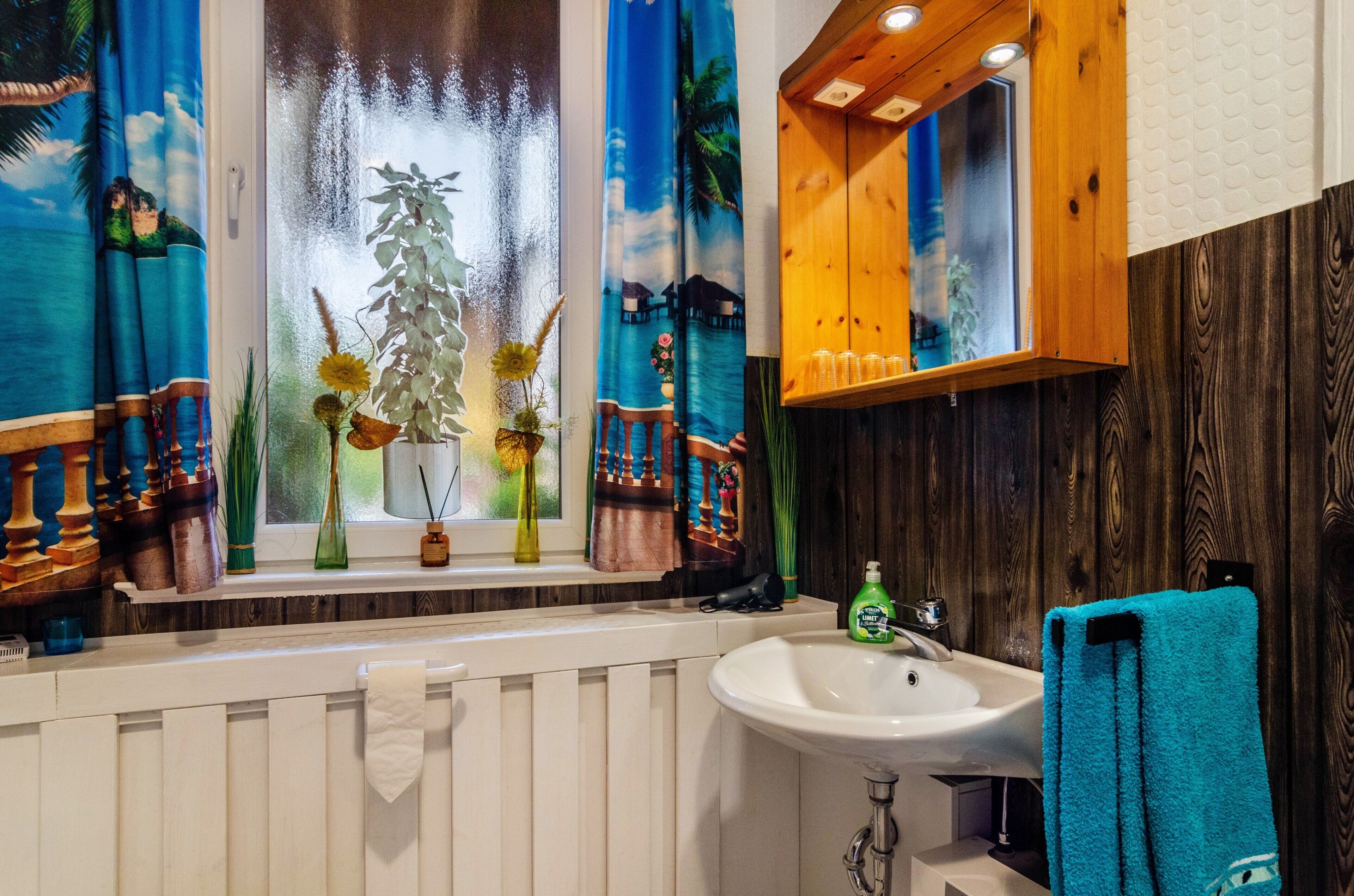 Ein Badezimmer mit Fenster, Waschbecken, Spiegel und Handtuchhalter.
