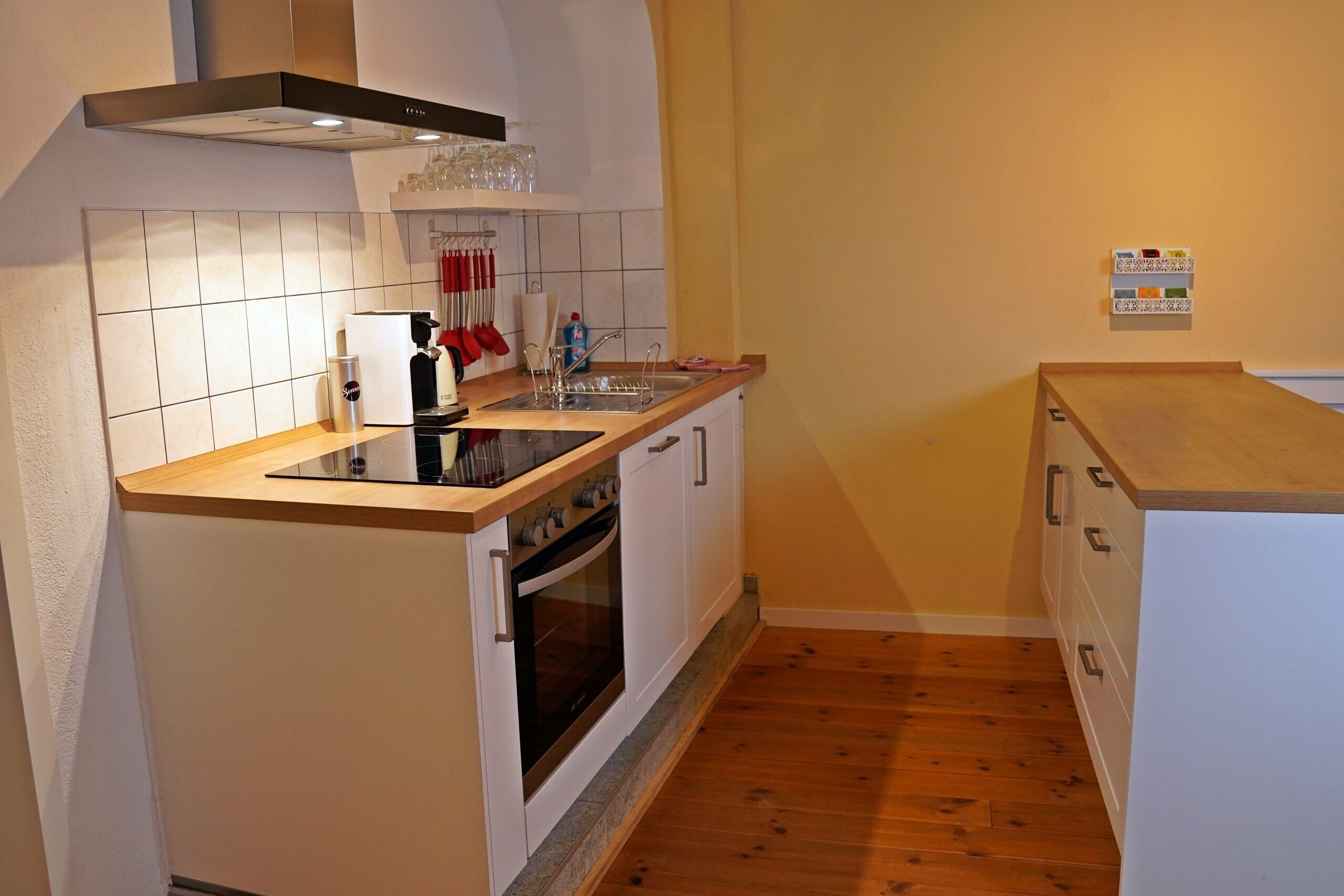 A compact kitchen with a stove, oven, sink, and wooden countertop.