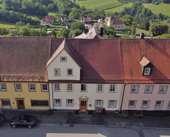 Une rangée de bâtiments de style européen traditionnel, avec des toits recouverts de tuiles rouges, une entrée centrale et une rue devant.