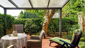 A covered patio with wicker furniture, a table, and a lounge chair.