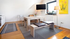 A modern kitchen with a dining area, a flat-screen TV, and a window with a view.