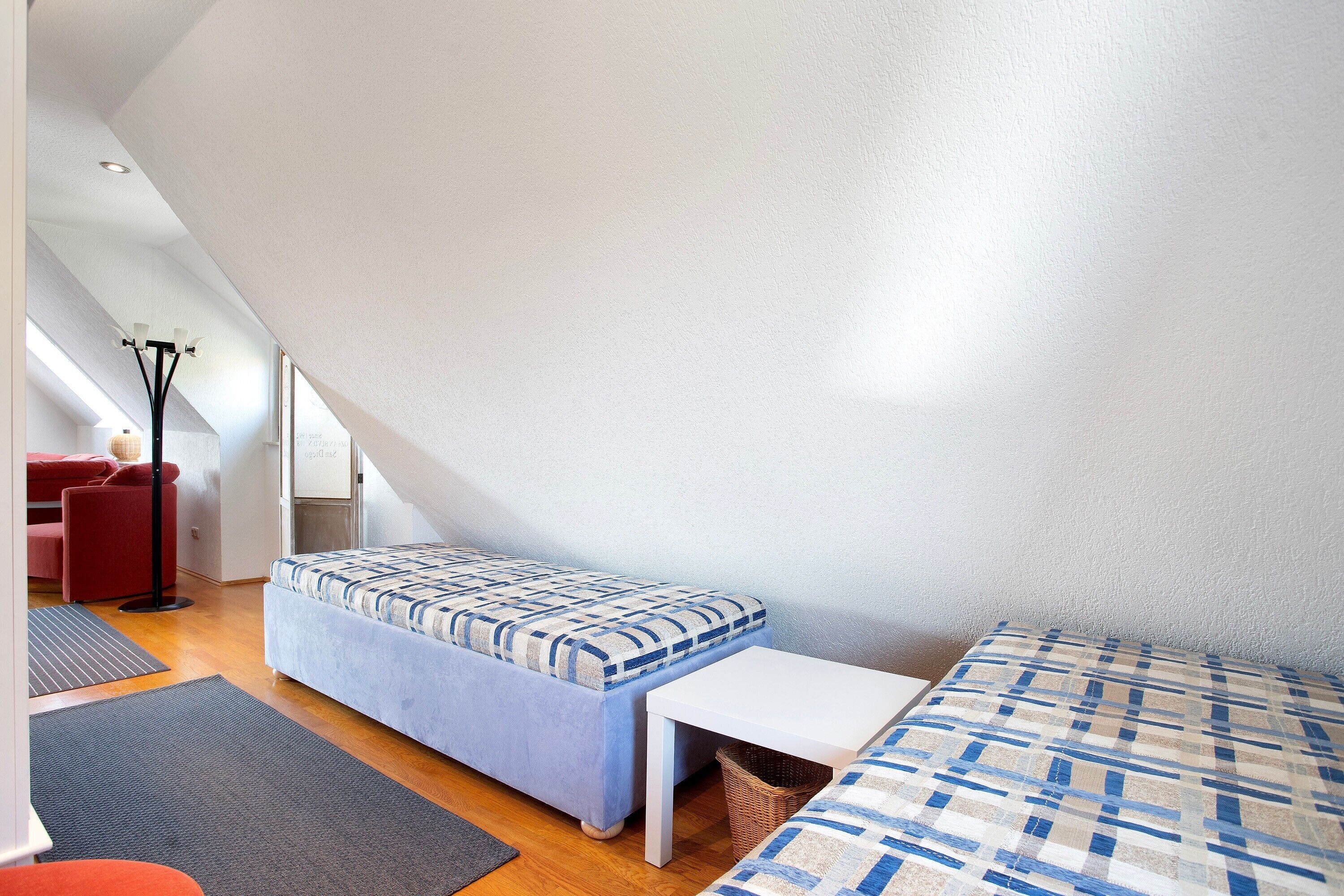 Een kleine, moderne kamer met een stapelbed, een tafeltje en een rode stoel.