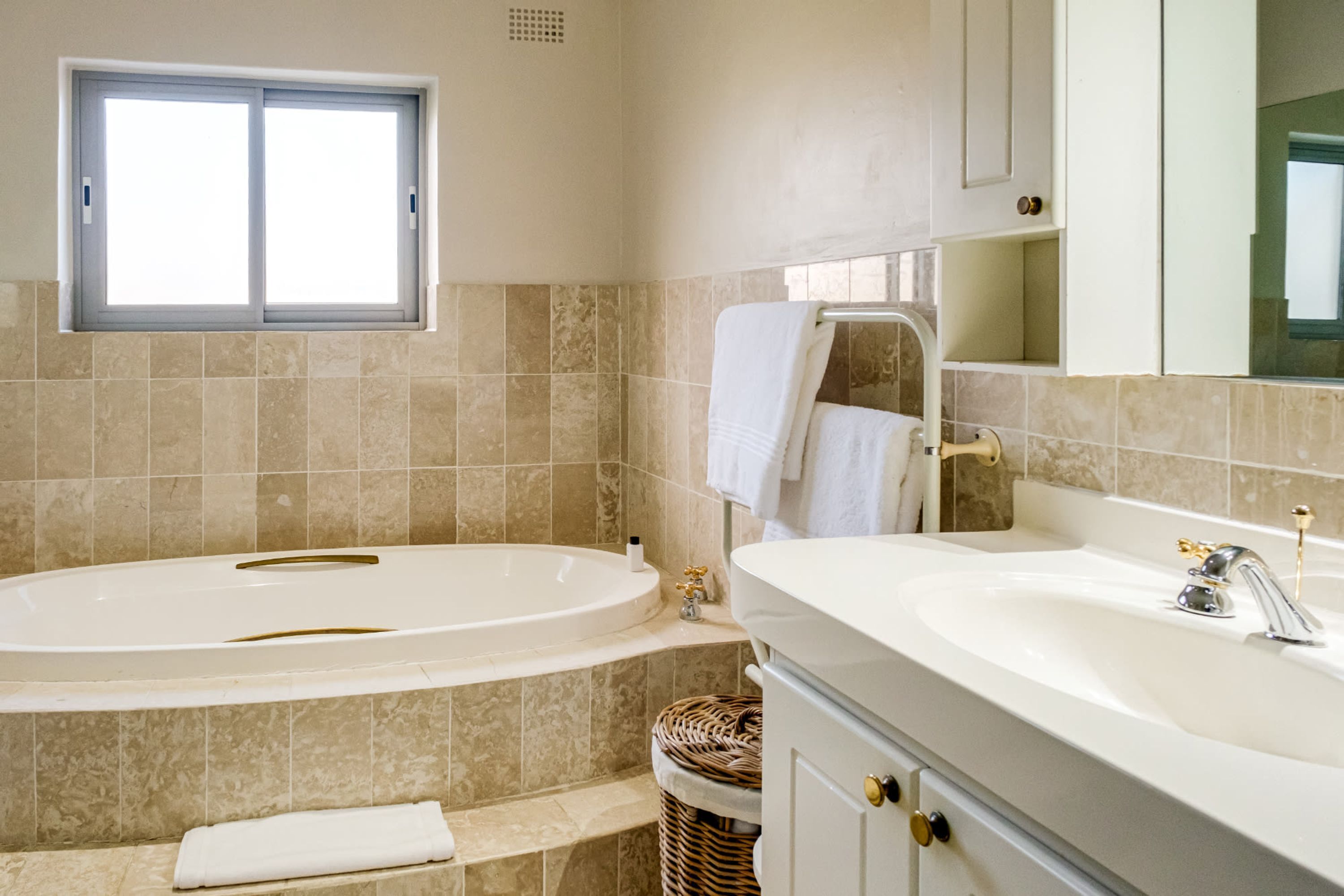A bathroom with a bathtub, a sink, and a window.