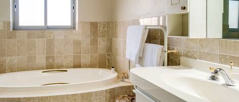 A bathroom with a bathtub, a sink, and a window.