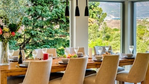 Mesa de comedor dispuesta para seis personas, con sillas, un florero y frutero.