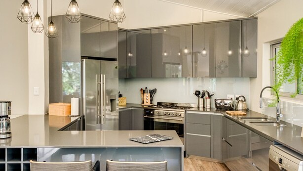 Una cocina moderna con electrodomésticos de acero inoxidable, una isla grande con taburetes de bar e iluminación colgante.