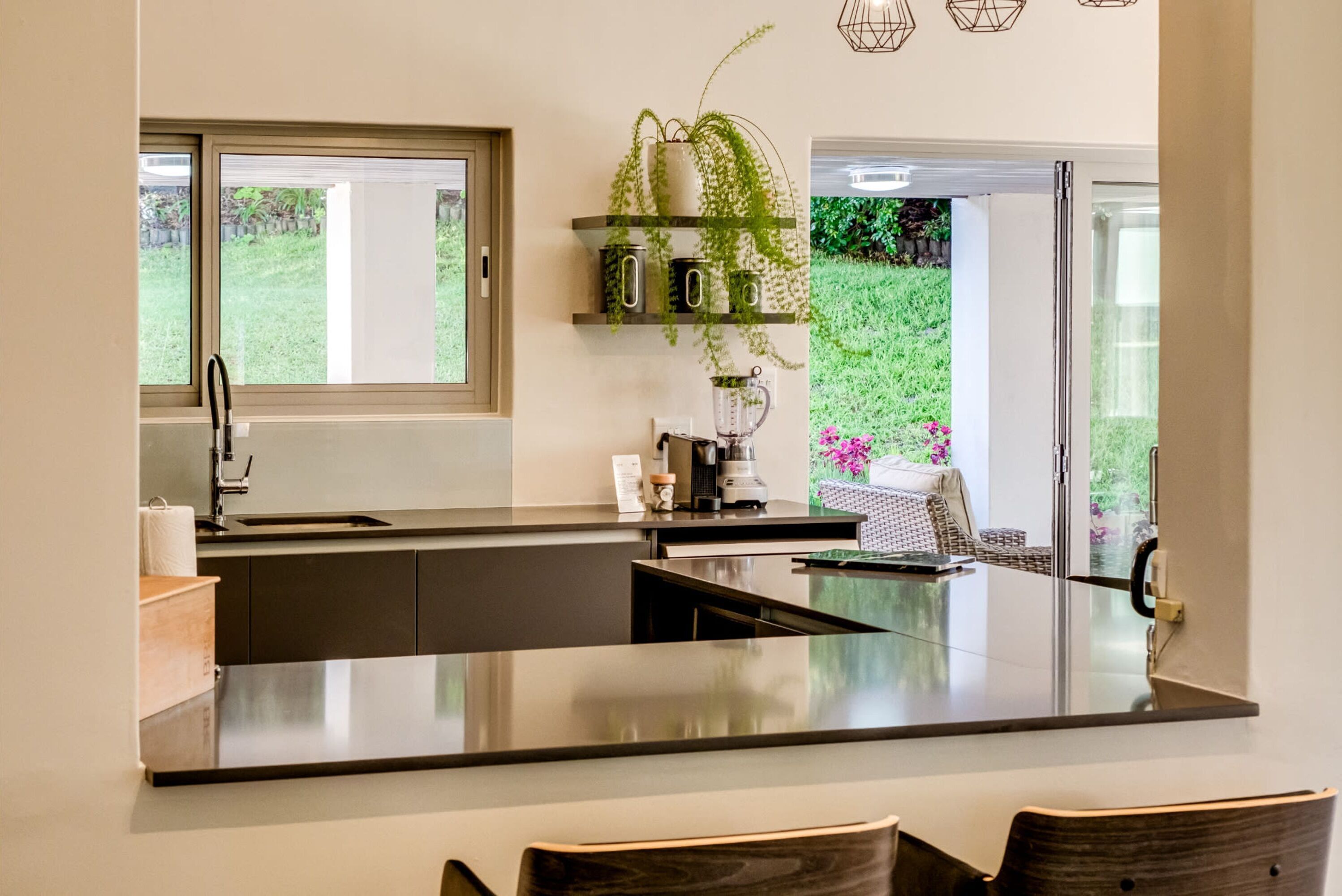 Une cuisine moderne dotée d’un grand îlot central, d’une fenêtre et offrant une vue sur un jardin.