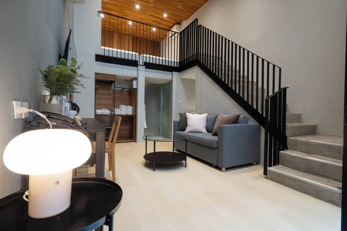 Ein modernes Wohnzimmer mit einem grauen Sofa, einem Couchtisch und einer Treppe mit schwarzen Geländern.