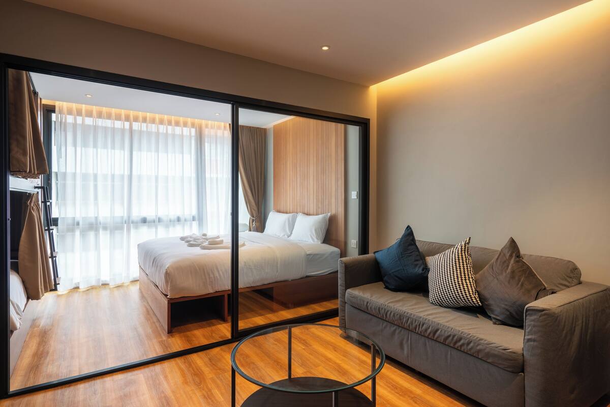 Ein modernes Hotelzimmer mit einem großen Bett, einer Sitzecke und einer Glaskonstruktion.