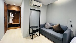 A modern living room with a grey sofa, a small black table, and a wardrobe. - Woodstory Boutique Hotel (Bangkok)