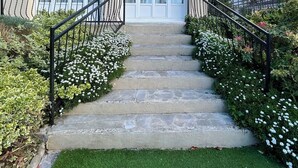 A two-story house with a beige exterior, a front porch, and a staircase leading to the entrance. - La Chaleureuse - Proche Cdg, Parc des Expositions, Disney, Astérix, Paris (Tremblay-en-France)