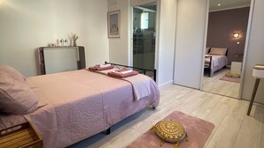 A modern bedroom with a large bed, a bedside table, a mirror, and a wardrobe. - La Chaleureuse - Proche Cdg, Parc des Expositions, Disney, Astérix, Paris (Tremblay-en-France)