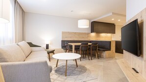 Une chambre d’hôtel moderne équipée d’un canapé, d’une table à manger, de chaises, d’un téléviseur et d’un coin cuisine.