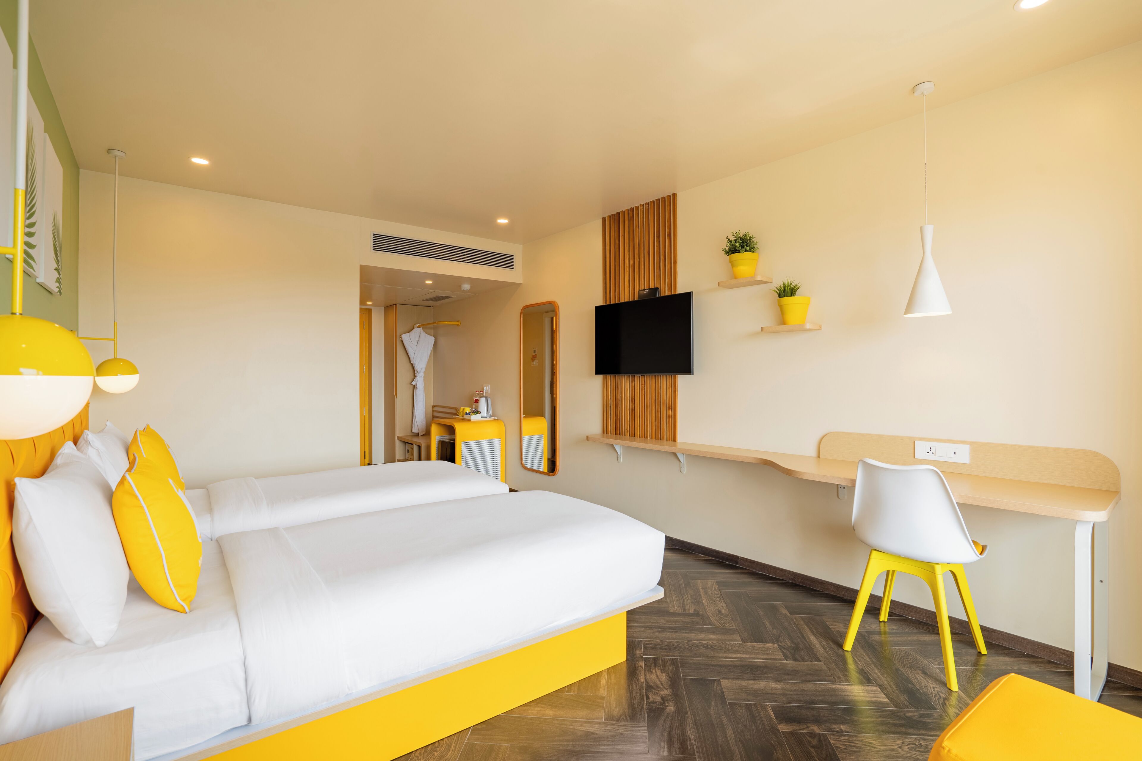 A modern hotel room with a bed, a desk, a chair, and a TV.