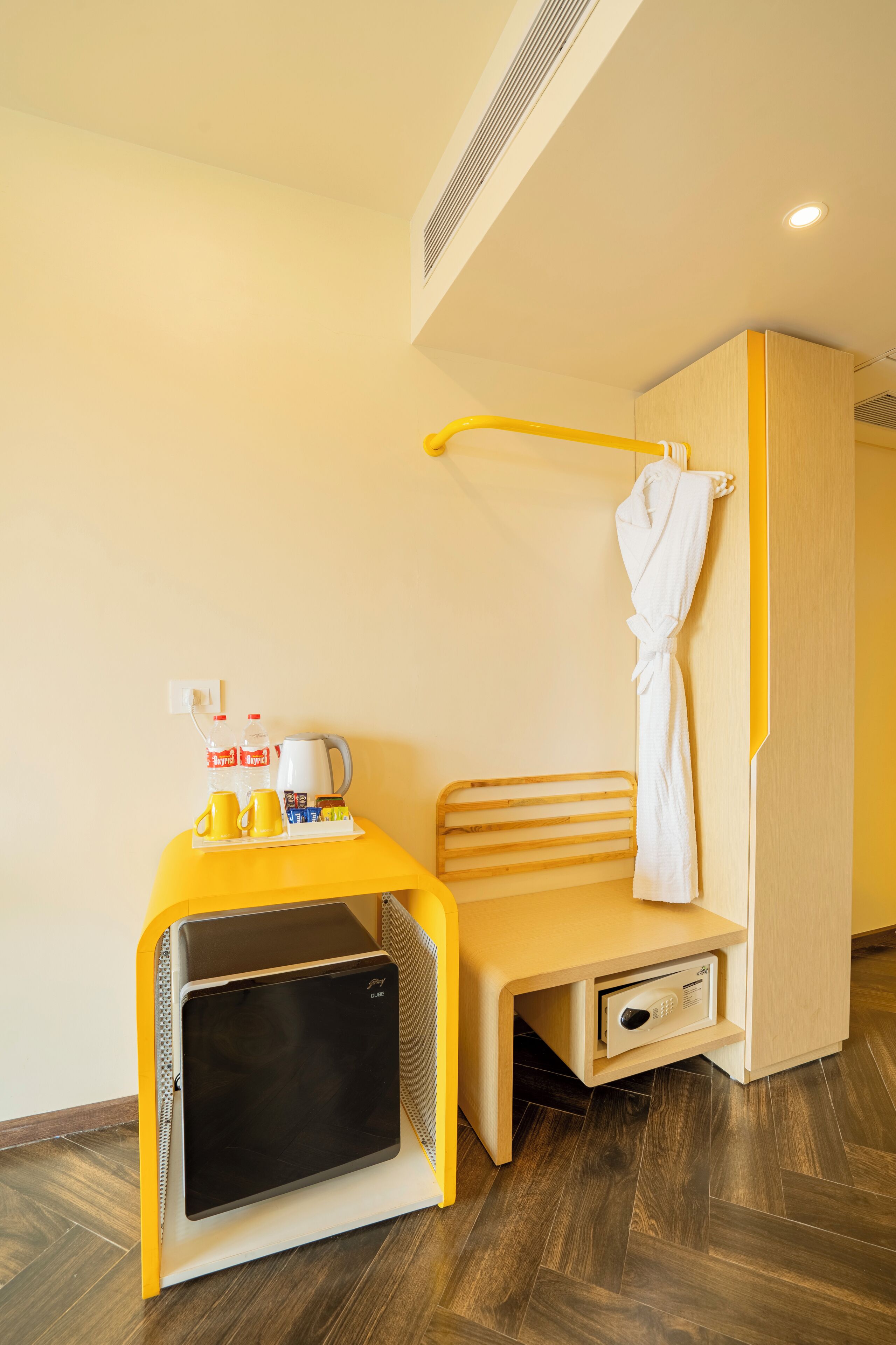 Een compacte hotelkamer met een bed, een klein bureau met waterkoker en een magnetron.