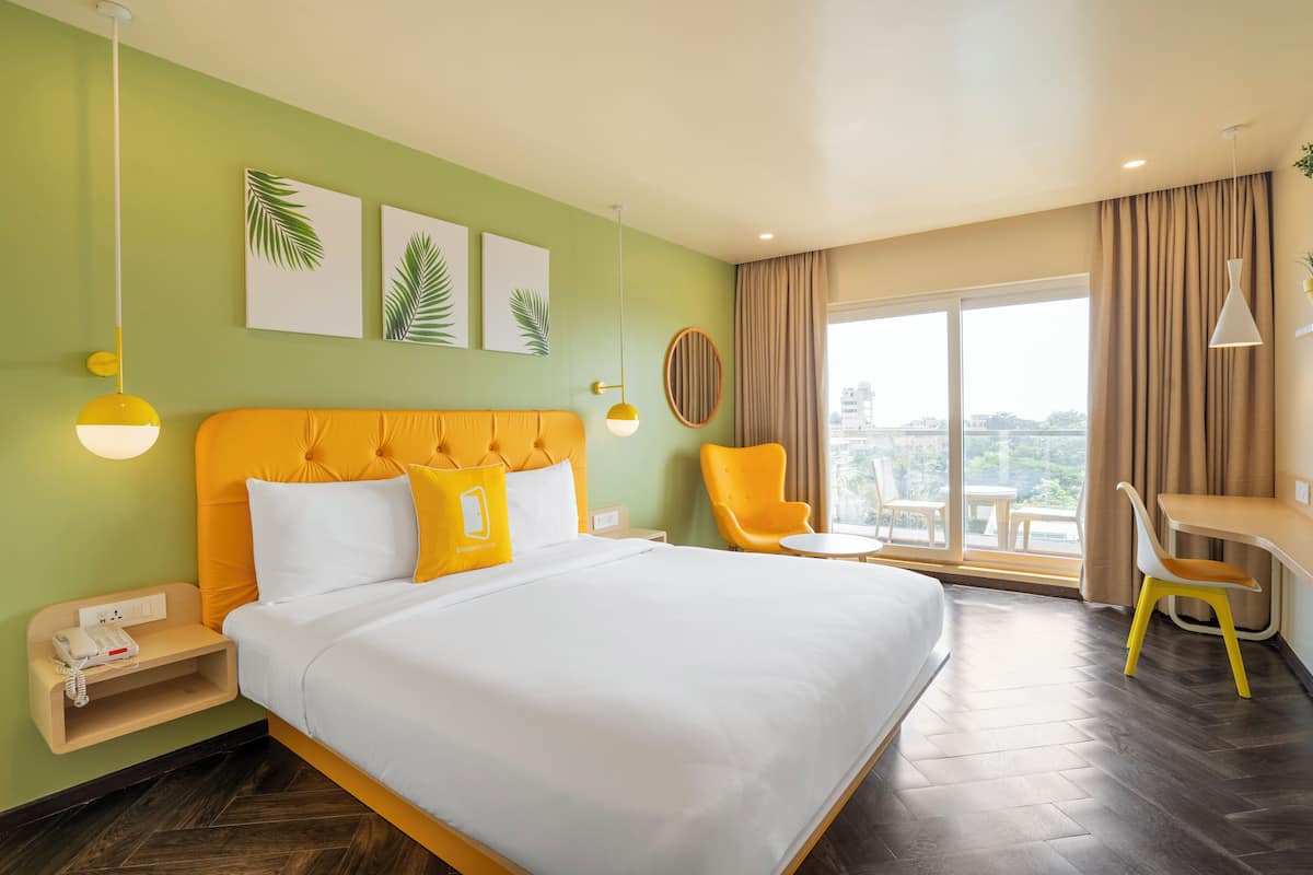 A hotel room with a bed, a desk, a chair, and a view of the outdoors.