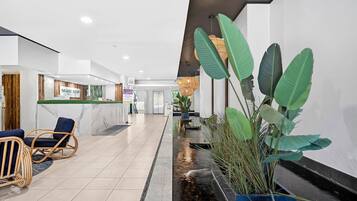 A hotel lobby with a reception desk, seating area, and a water feature.