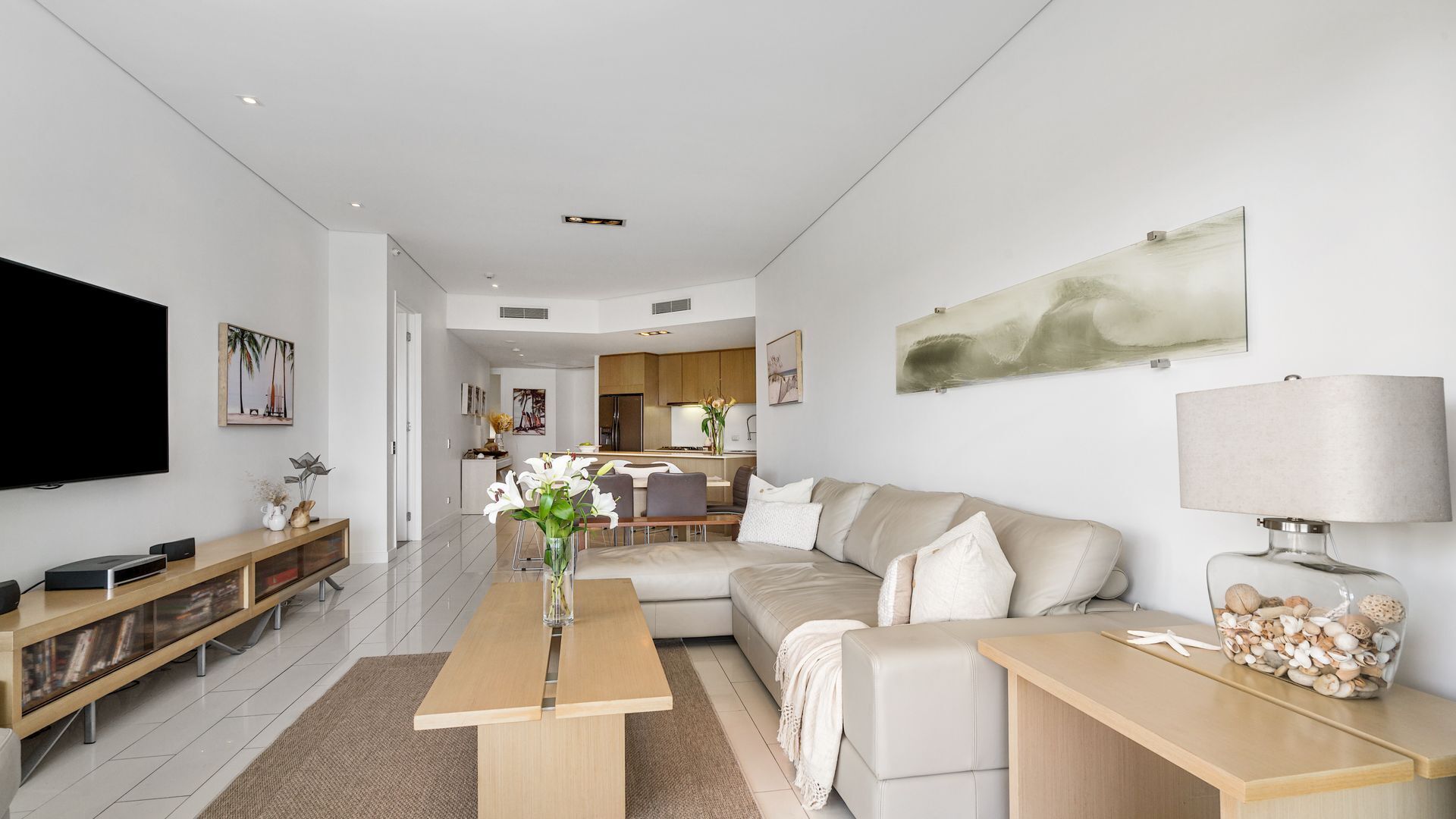 A modern living room with a sofa, coffee table, TV, and artwork.