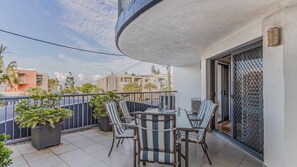 Un balcon avec une table et des chaises, des plantes en pot et une vue sur les immeubles.