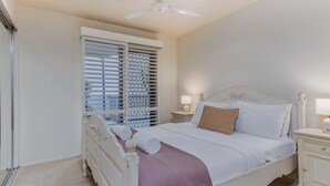 A bedroom with a bed, bedside tables, a ceiling fan, and a window with blinds. - Breakwater Views Apartment 2 Cabarita Beach (Cabarita Beach)