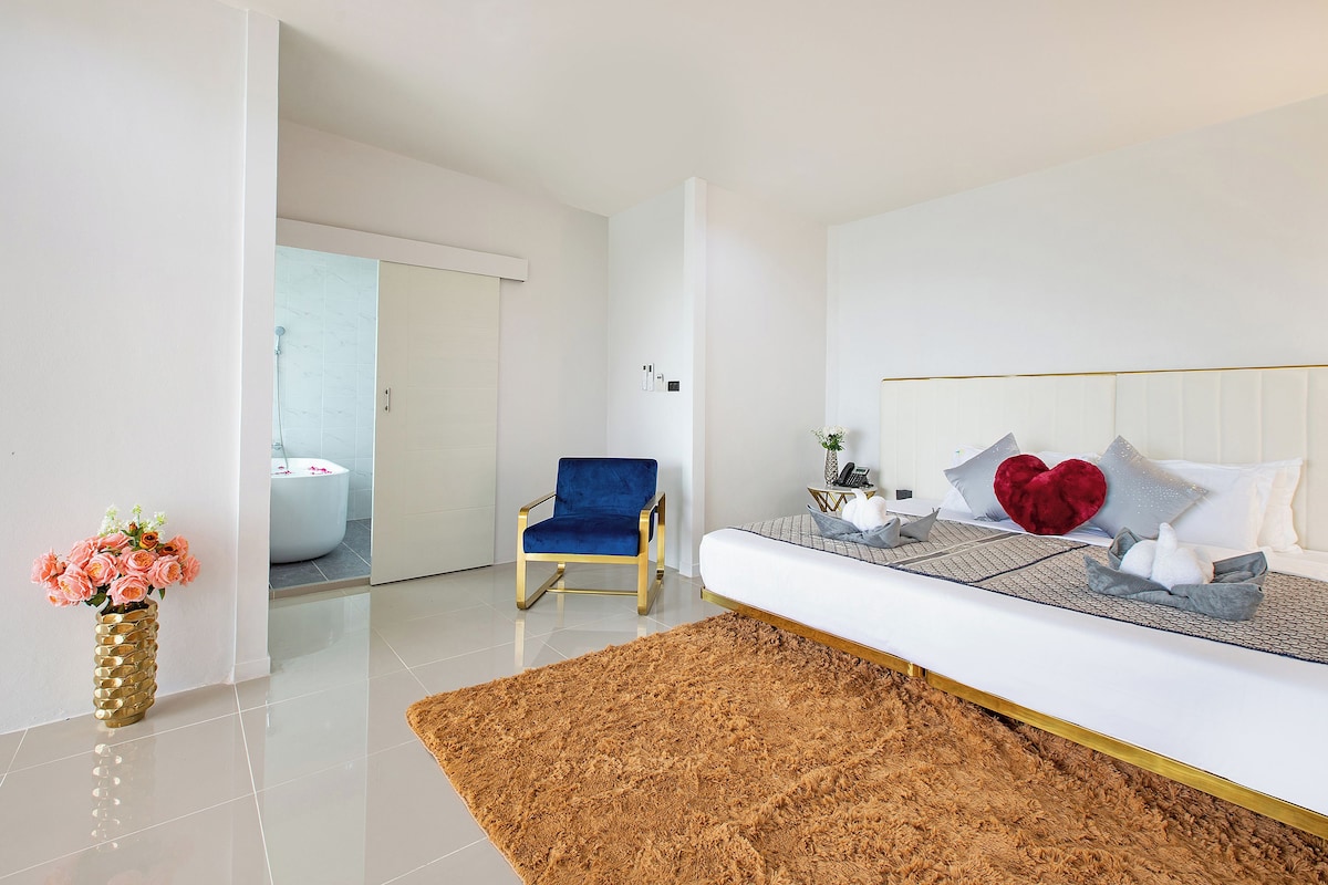 Un dormitorio moderno con una cama blanca, una silla azul y un tapete mullido.