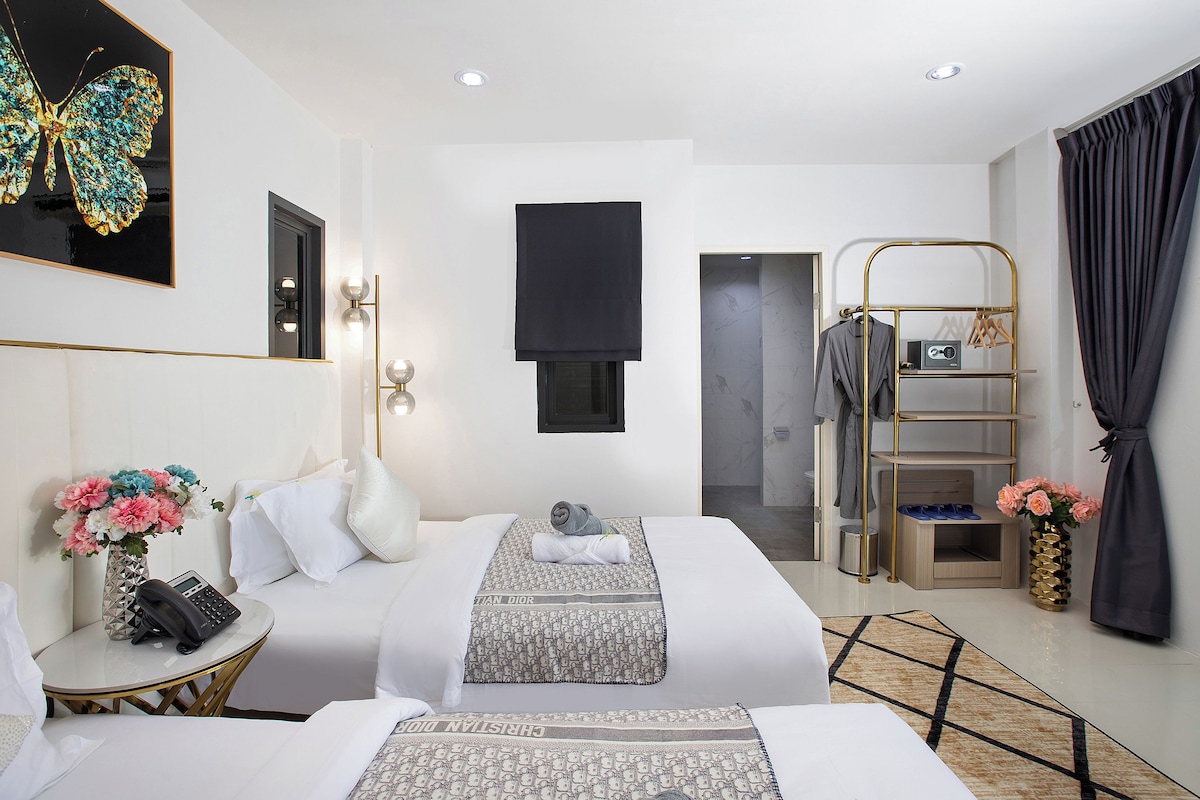 Habitación de hotel con cama, mesita de noche y televisor de pared.