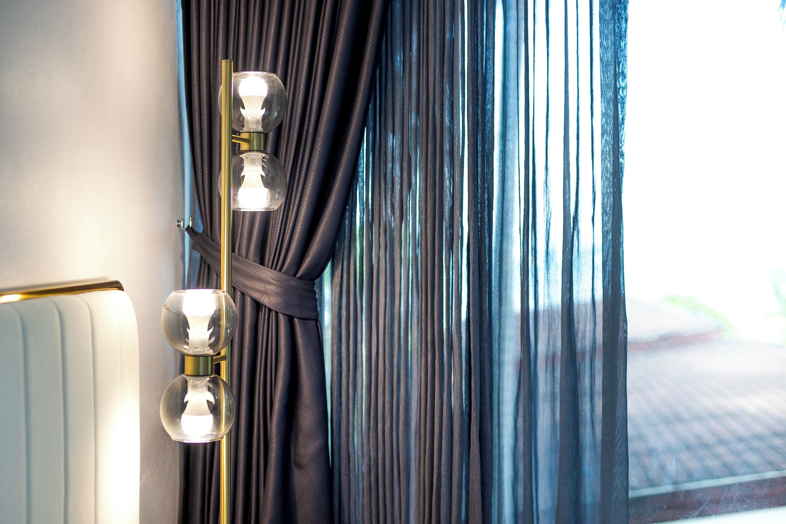 A room with a wall-mounted light fixture and a window with dark curtains.
