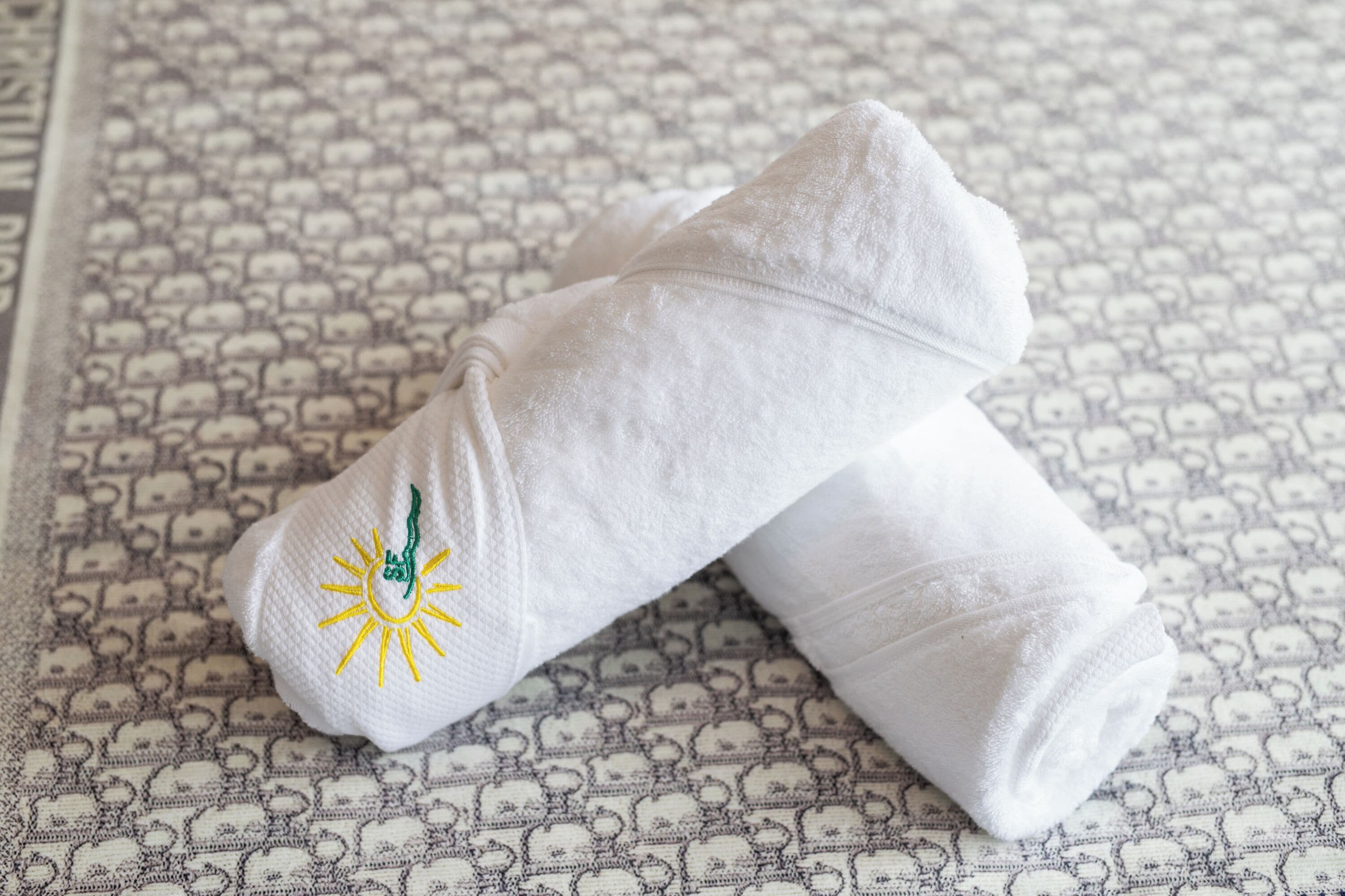 A white towel with a sun design on a patterned floor.