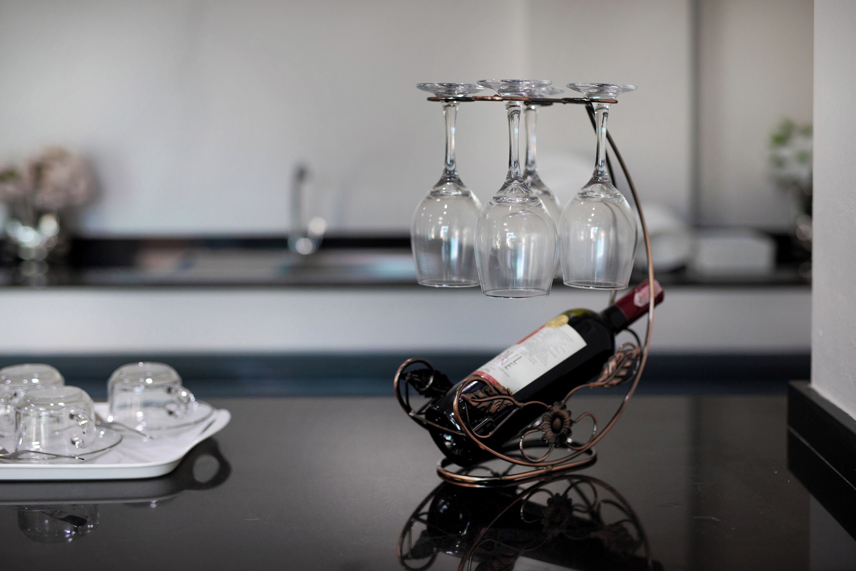 Une bouteille de vin posée sur un présentoir, avec plusieurs verres disposés sur un plateau.