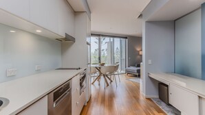 A modern kitchen with a dining area, large windows, and a view of palm trees. - Resort Apartment 4304 at Bells Boulevard (Kingscliff)