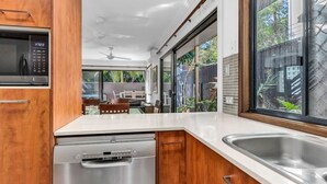 A modern kitchen with a Bosch dishwasher, a microwave, and a large window overlooking a garden.