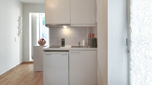 A compact kitchen with white cabinets, a built-in oven, and a dishwasher. - Cozy Garden Studio (Athens)