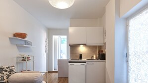 A compact kitchen with white cabinets, a dishwasher, and a small countertop. - Cozy Garden Studio (Athens)