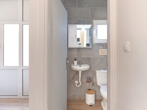 A modern bathroom with a white sink, toilet, and a mirror above the sink. - Cozy Garden Studio (Athens)